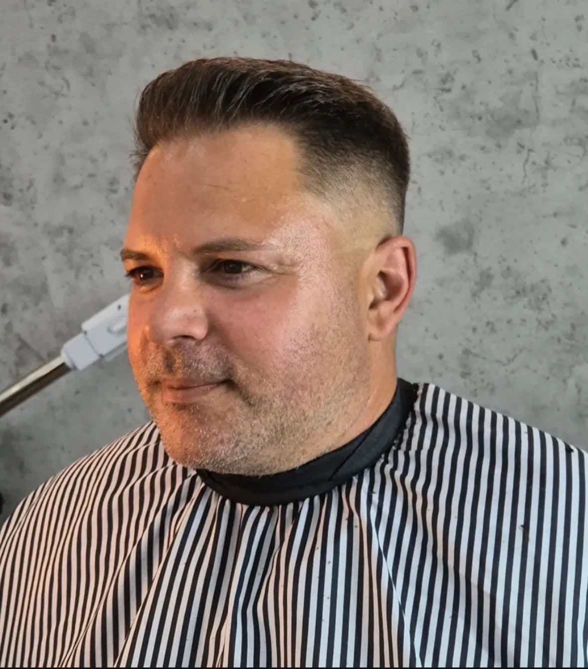Row of black vintage barber chairs in front of large round mirrors.